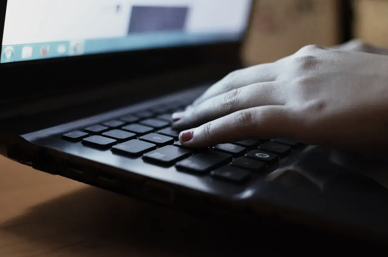 A hand typing on a laptop keyboard.